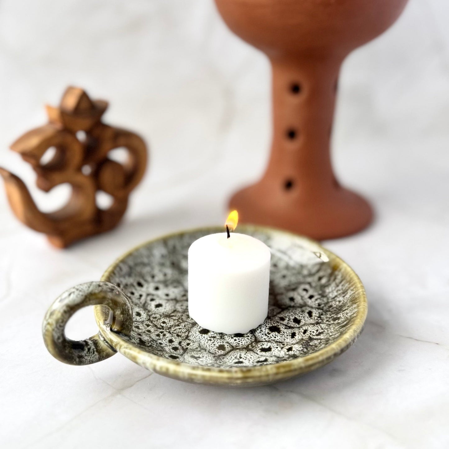 Ceramic incense burner with a candle on a decorative plate on a white background