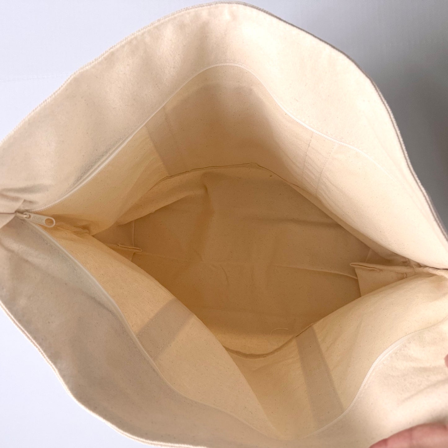Beige fabric bag with a zipper on a light gray background