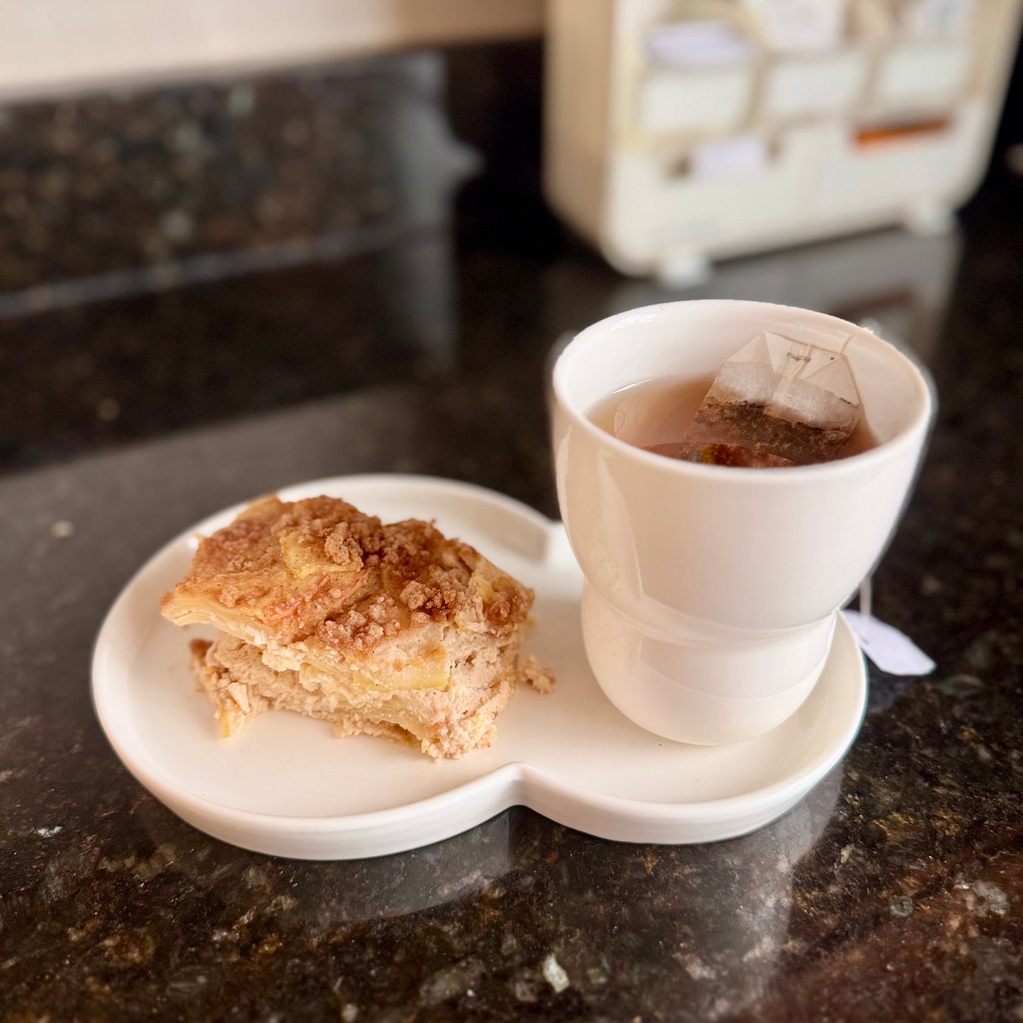 White cup with tea bag and pie on a marble surface