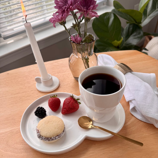 Cup of coffee with a plate of cookies and strawberries on a wooden table.