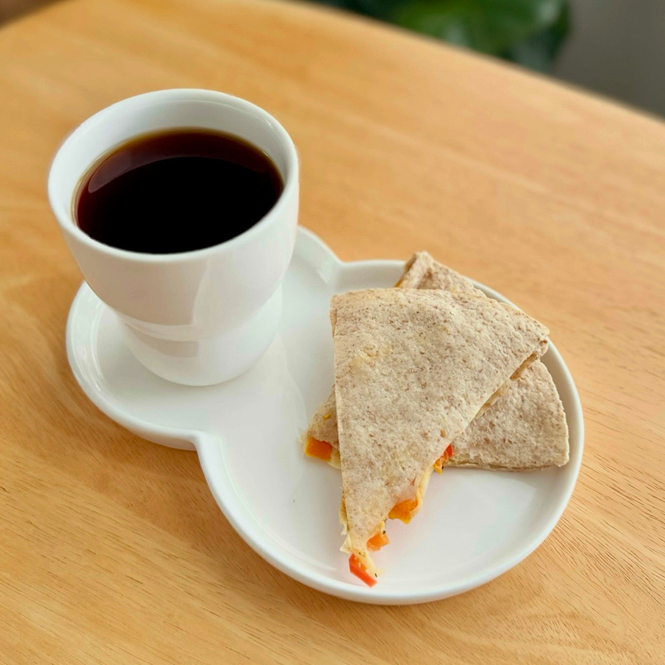 White cup of coffee and a sandwich on a white tray on a wooden table
